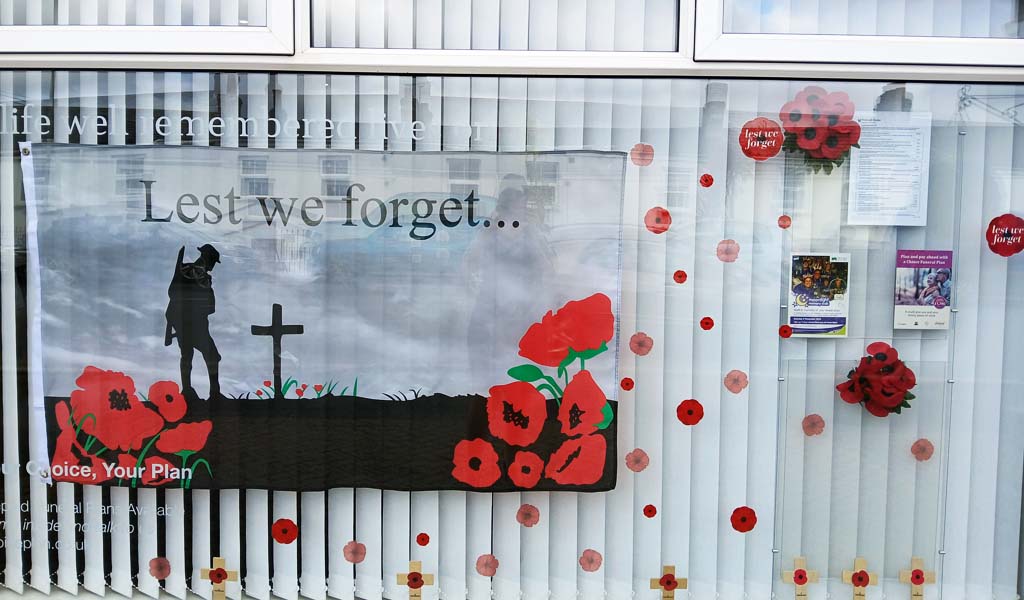 A Remembrance Day window display for Personal Choice Funeral Directors St. Austell, Mount Charles Road branch. It has poppies in the window and a solider on a battlefield in the window.